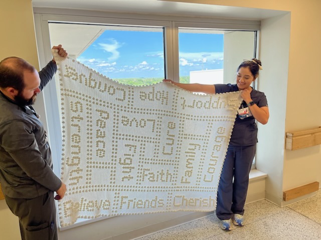 Jim's caregivers hold up the blanket made by David Warren's mother-in-law