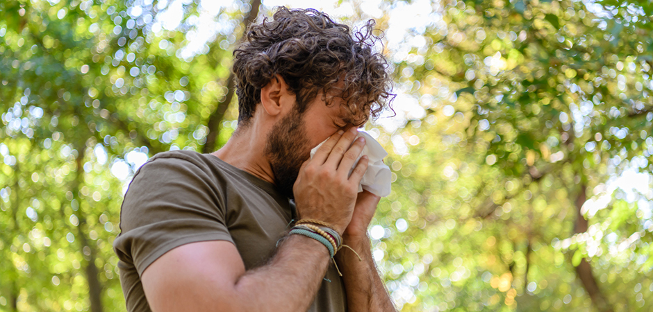 Man taking a walk in the woods and sneezing