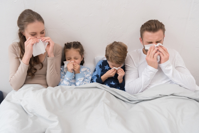 two children in bed with their sick parents
